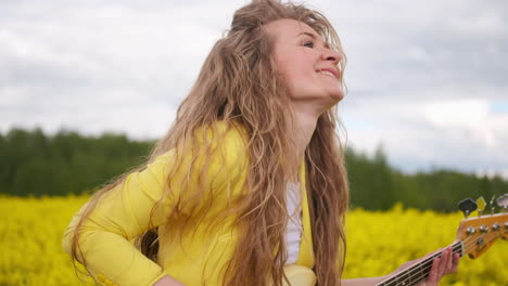 Manual-movement-of-the-camera-following-the-dancing-guitar-player.-A-beautiful-girl-in-a-yellow-jacket-plays-a-guitar-in-a-field-of-rapeseed.